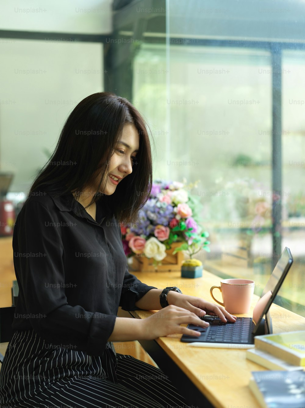 Portrait of female freelancer using digital tablet with keyboard on counter bar in cafeteria