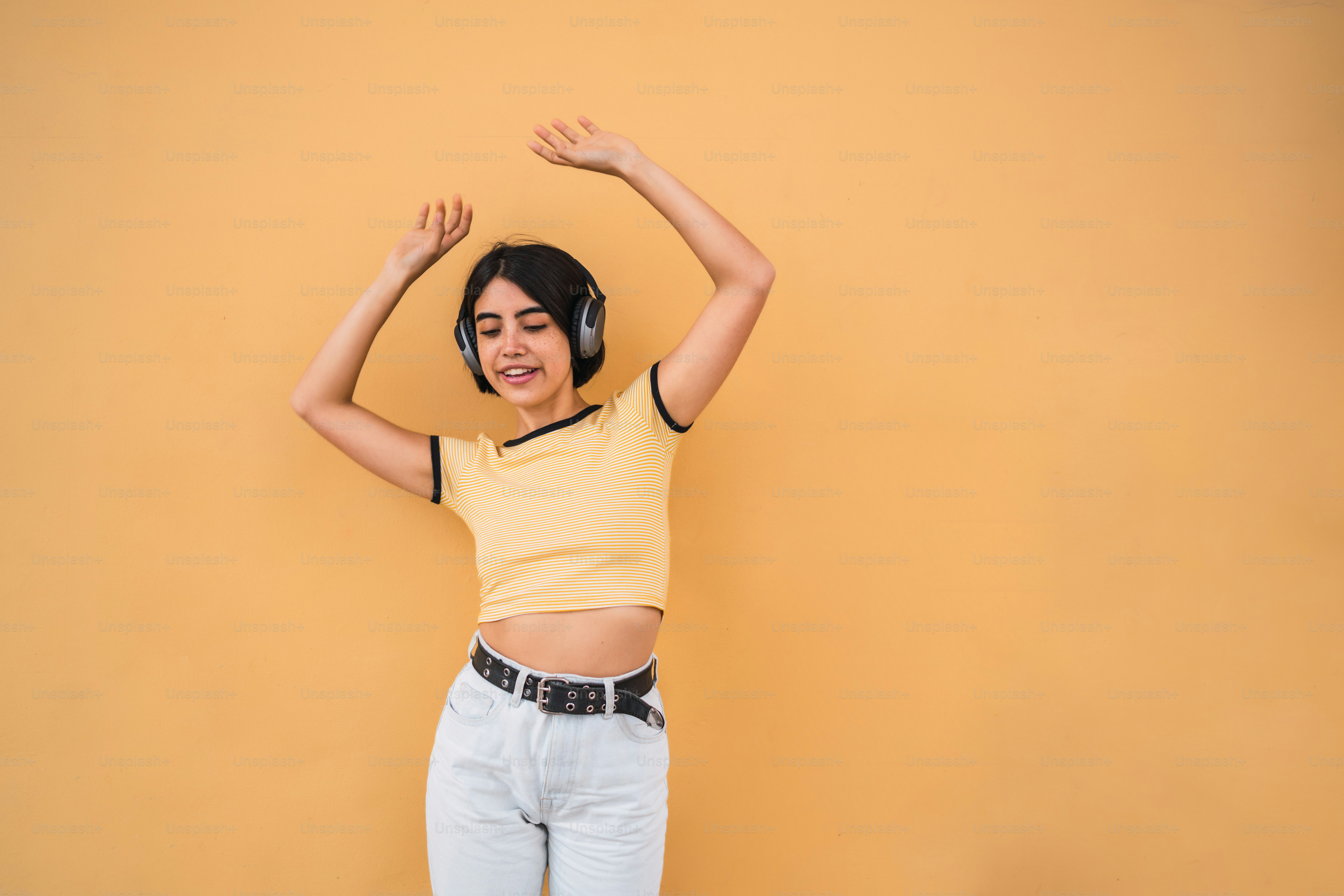 Portrait of young latin woman listening to music with headphones ...