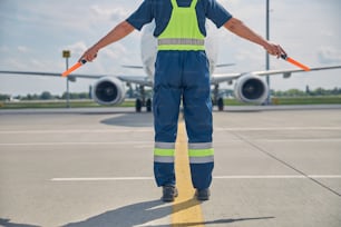 Cropped photo of a marshaller making the hold signal to the pilot in the airplane