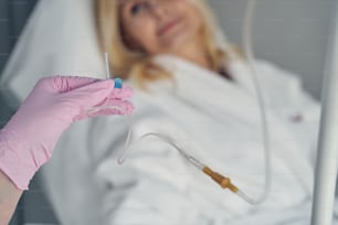 Behandschuhte Hände eines qualifizierten Arztes, der den intravenösen Katheter für die Hauterneuerung hält