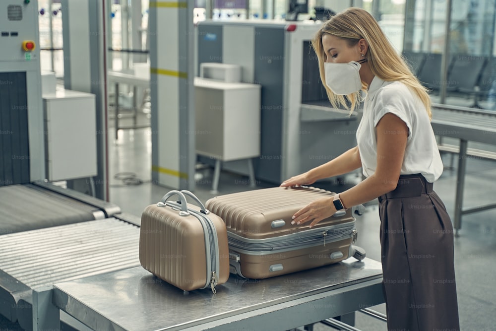 Pretty long haired blonde standing in semi position while doing checkup of her luggage