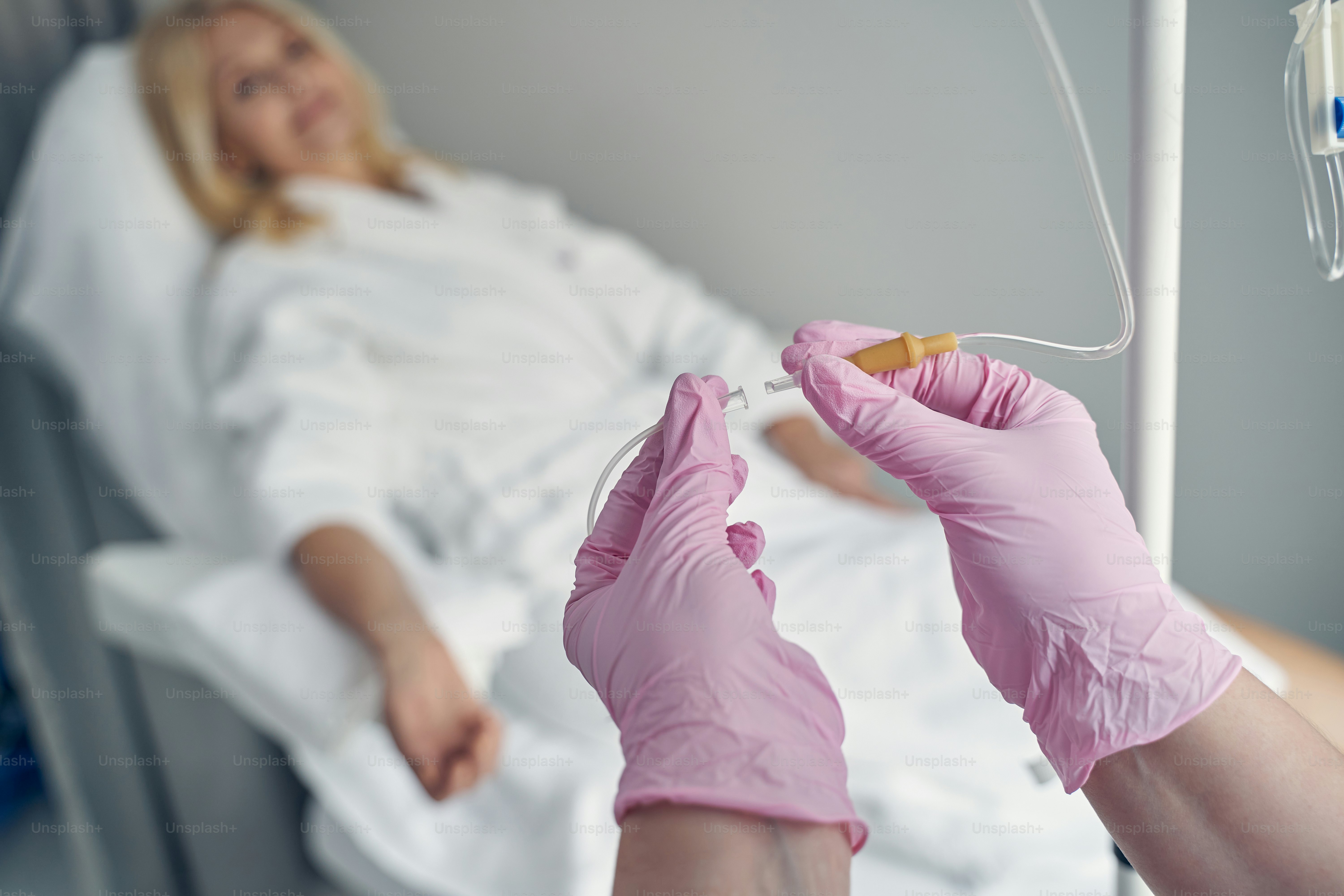 Hands of professional doctor matching transparent plastic tubes before setting a dropper with vitamins