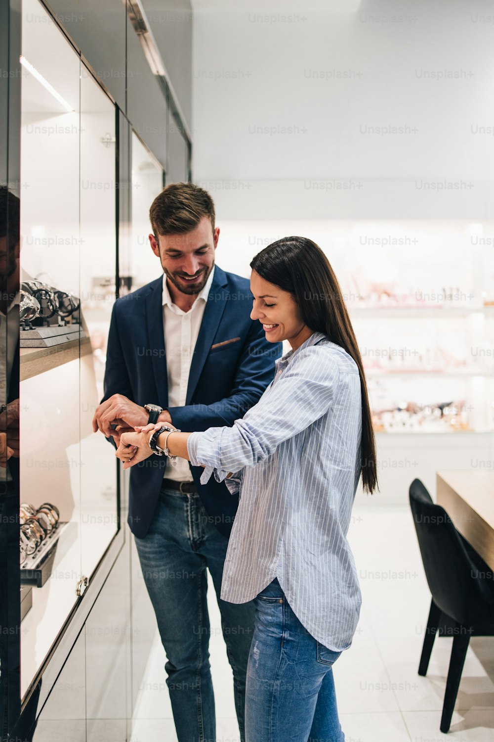 시계를 시험해보고 사면서 현대 보석 가게에서 쇼핑을 즐기는 아름다운 커플.