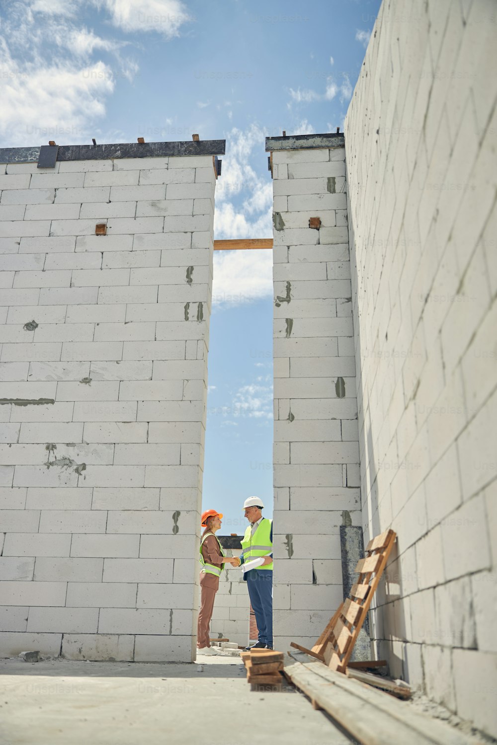 Vista lateral de una joven contratista y un ingeniero civil saludándose afuera