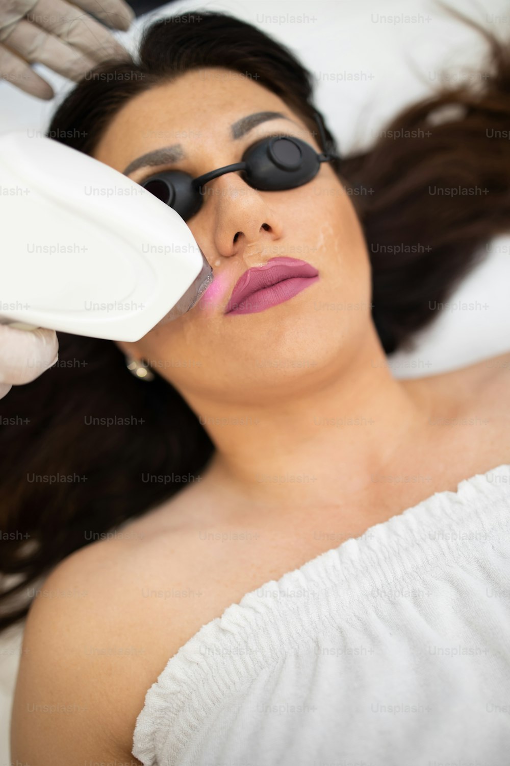 Young beautiful woman receiving face skin epilation treatment. Modern body care and cosmetics concept.