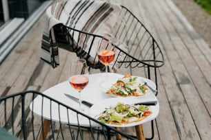 Homemade pizza and aperol drink on modern wooden terrace, dinner for two. Delicious pizza and cocktails for home celebration. Summer vacation and resort.