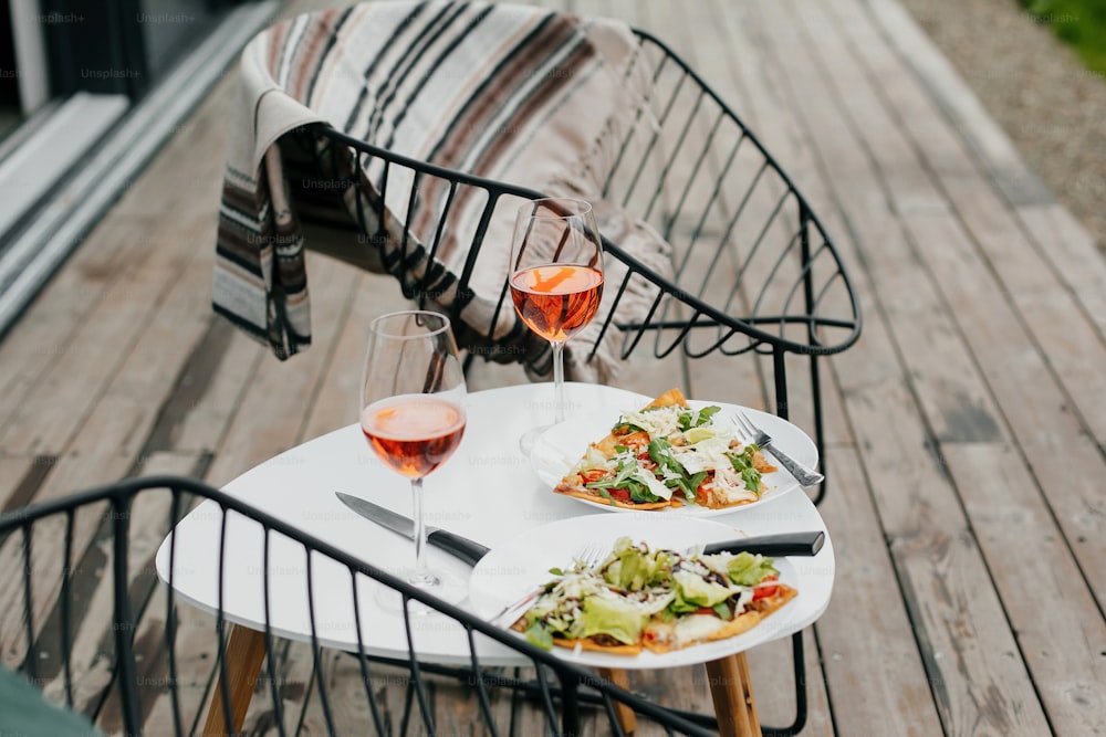 Homemade pizza and aperol drink on modern wooden terrace, dinner for two. Delicious pizza and cocktails for home celebration. Summer vacation and resort.