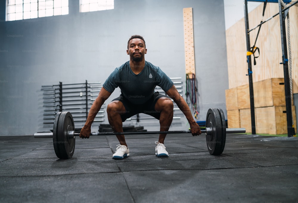 Portrait of young athlete doing exercise with a barbell.