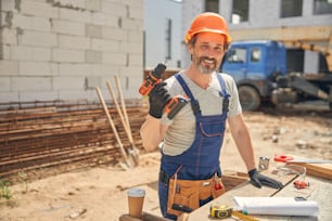 Front view of a cheerful male worker posing for the camera at the building site