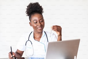 Female doctor in white coat holding blood test tubes in hands while wrapped up in work at modern lab. Female life science professional holding glass cuvette. Healthcare and biotechnology concept.