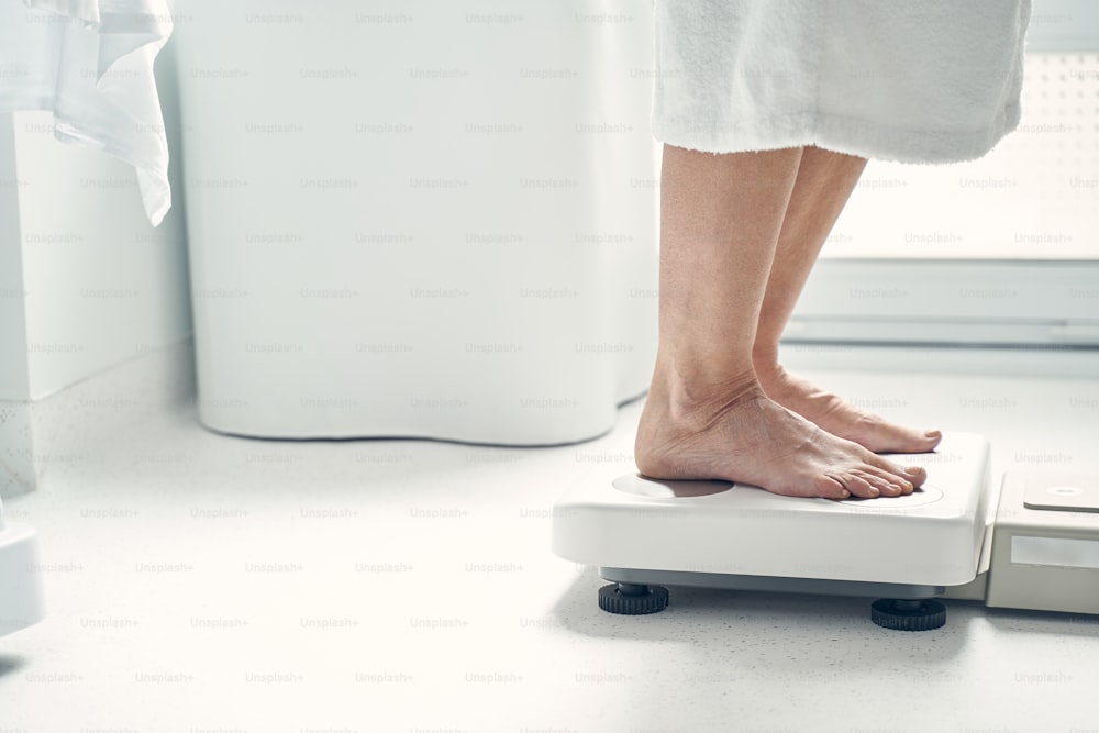 Adult woman measuring body parameters while standing on professional medical tool