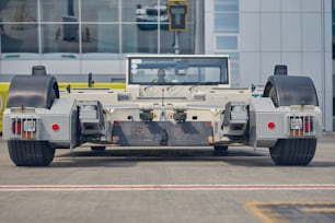 Skilled Caucasian airport worker in sunglasses and uniform driving a ground vehicle at the airport