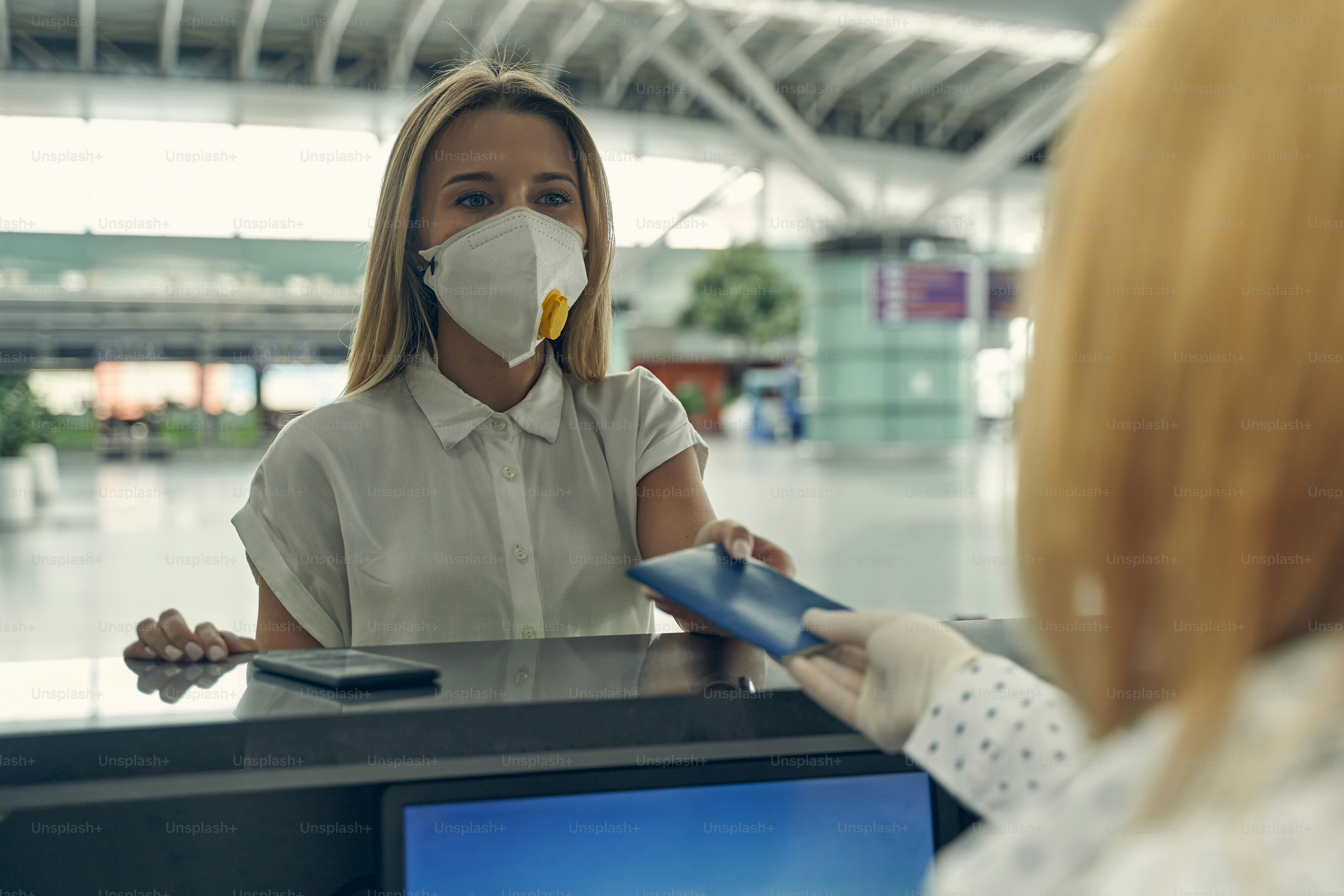 Attentive blonde woman standing at registration board while preparing for her flight