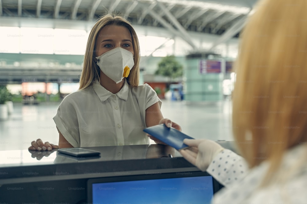Attentive blonde woman standing at registration board while preparing for her flight