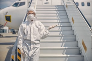 Front view of a female in a hazmat suit standing at the bottom of the stairs