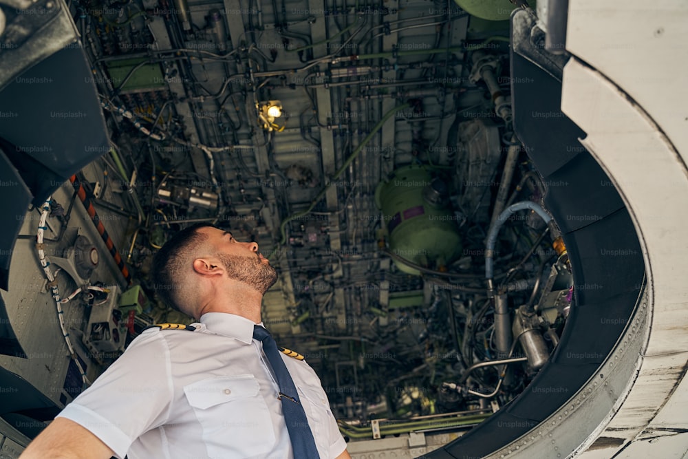 飛行機の下腹部を見上げる真面目な男性パイロットのローアングル