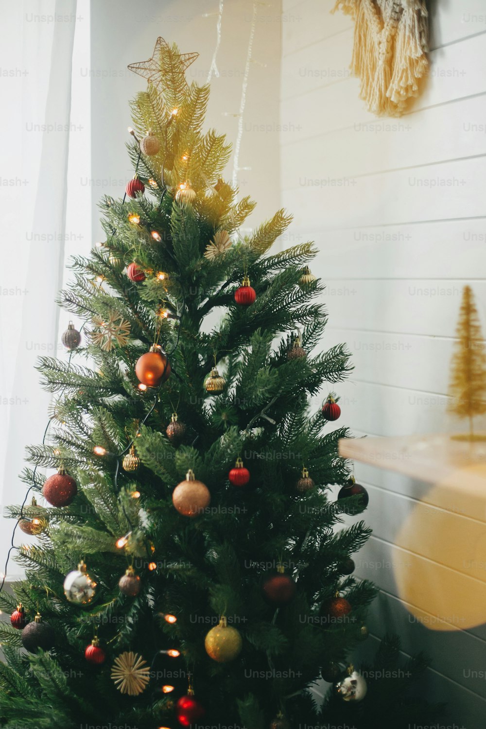 Foto Árvore de Natal decorada modernamente com enfeites vermelhos e  dourados e luzes festivas. Ornamentos de glitter brilhantes pendurados na  árvore de Natal, decoração do quarto escandinavo para férias de inverno –