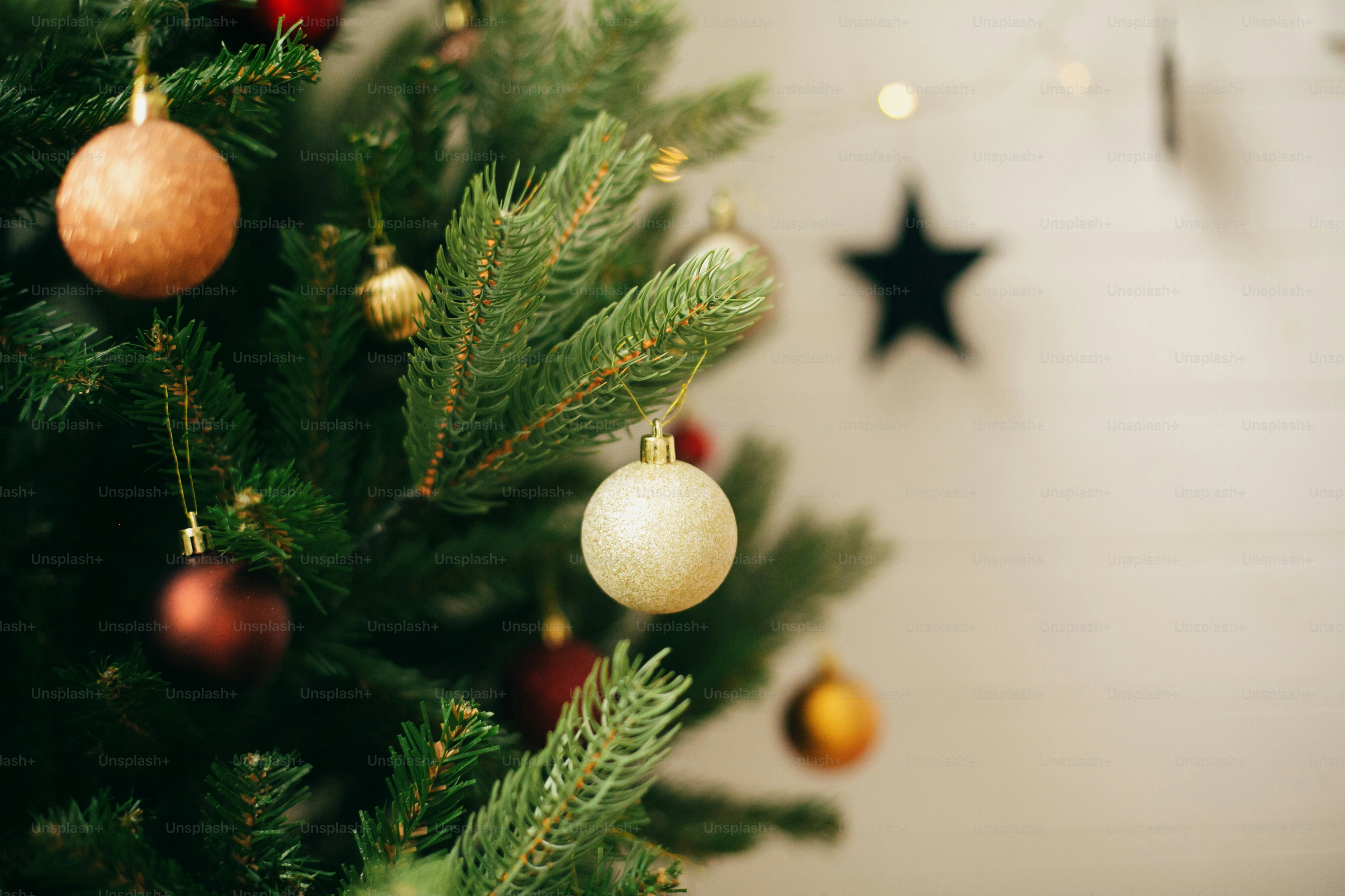 Christmas tree branches decorated with gold and red baubles against a blurred background