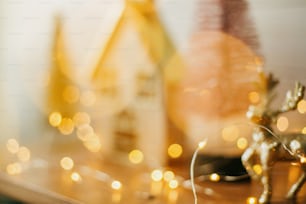 Fundo abstrato de Natal. Iluminação amarela bokeh na aldeia de fadas em miniatura. Imagem borrada de casa e árvores de purpurina em luzes festivas douradas. Feliz Natal e Boas Festas