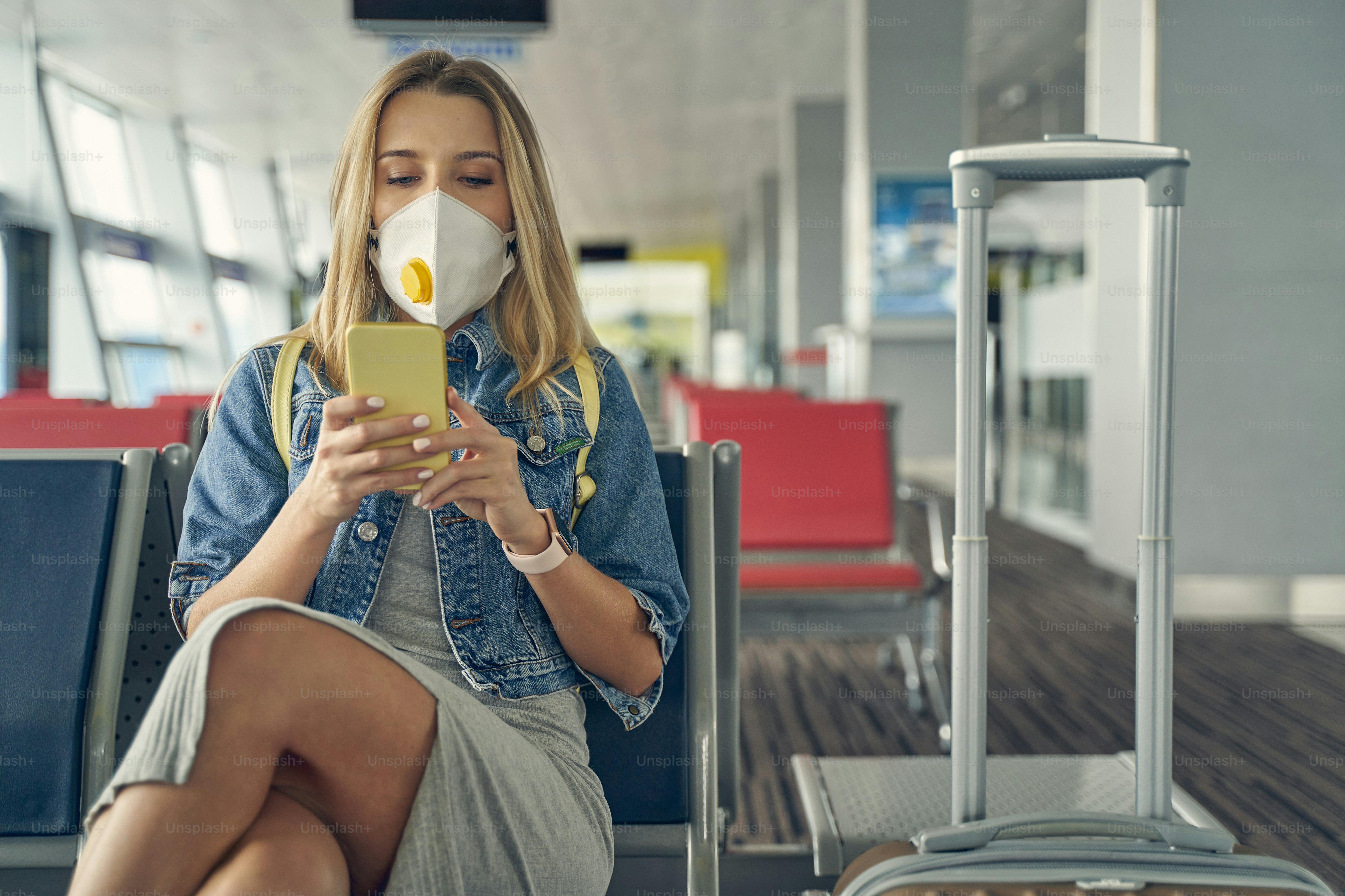 Beautiful long haired woman wearing protective mask while sitting in the departure lounge