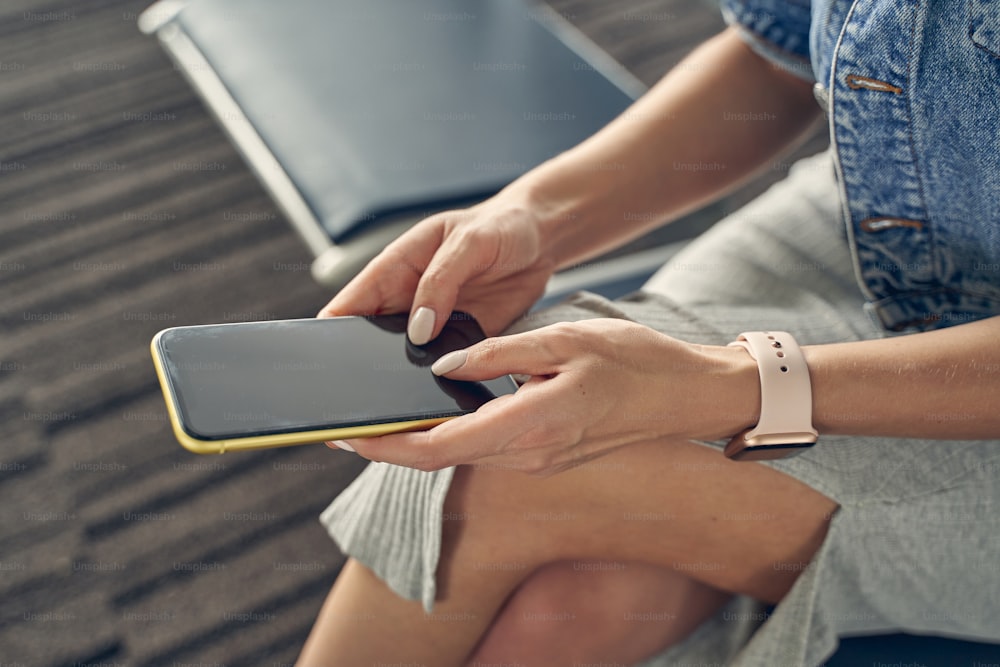 Focused photo on young woman sitting in the departure lounge and chatting with her boyfriend