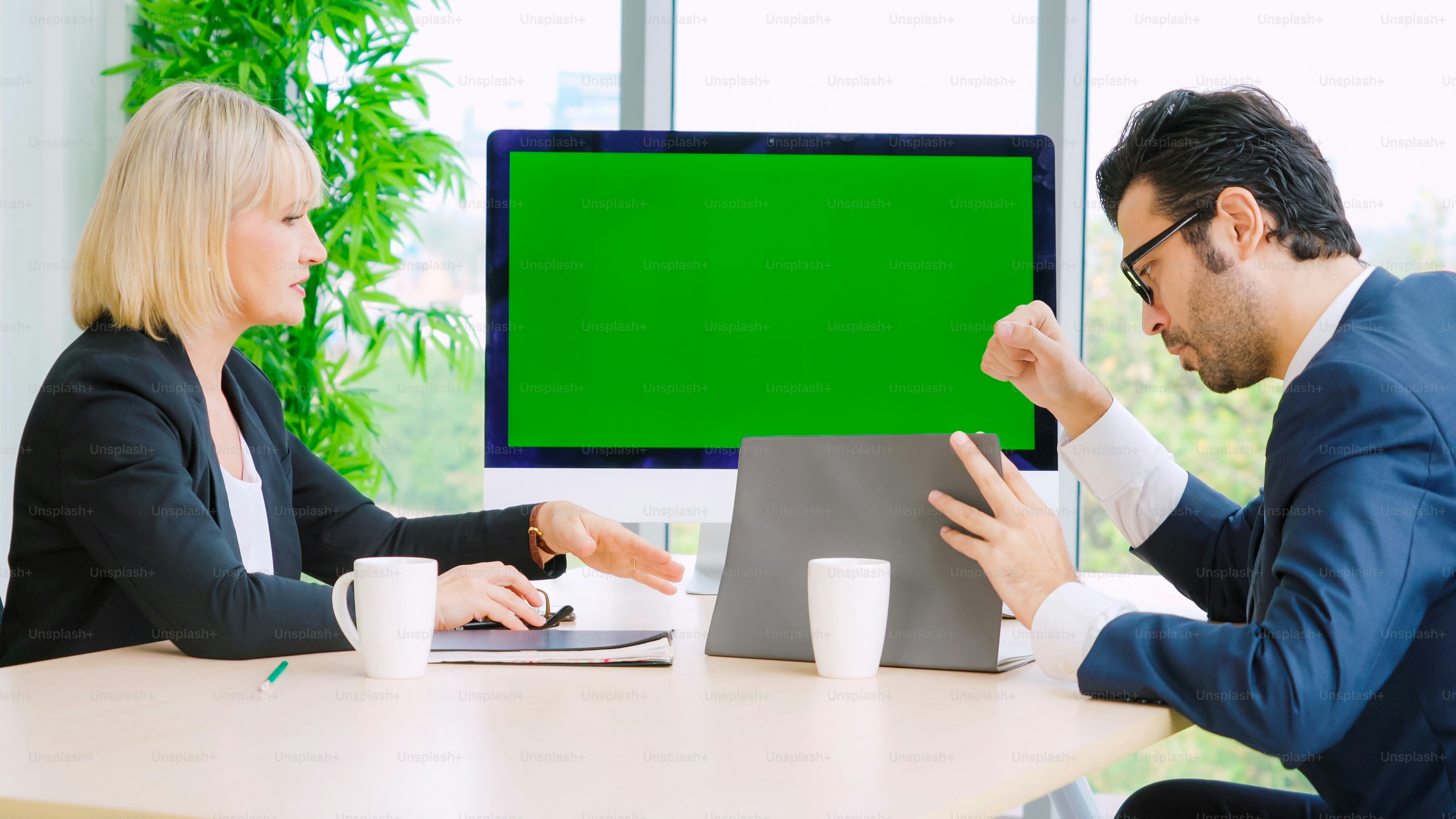 Gente de negocios en la sala de conferencias con pantalla verde chroma key TV o computadora en la mesa de la oficina. Grupo diverso de hombres y mujeres de negocios en reunión en videoconferencia.
