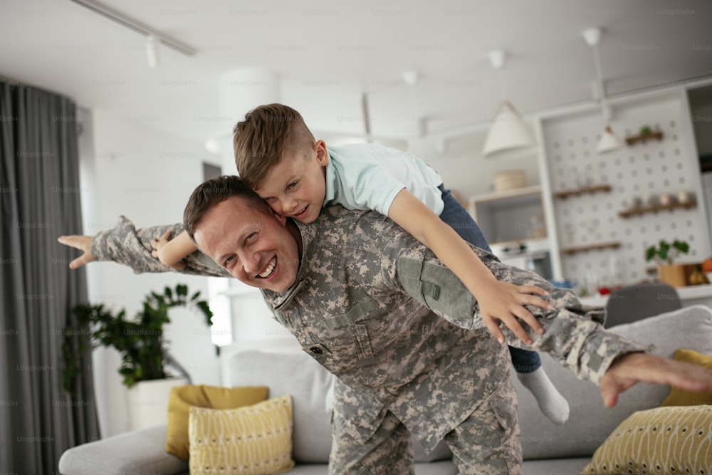 幸せな兵士は息子と遊んでいます。子供と家で楽しんでいる兵士。