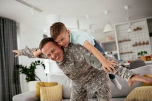 Happy soldier play with his son. Soldier enjoying at home with children.