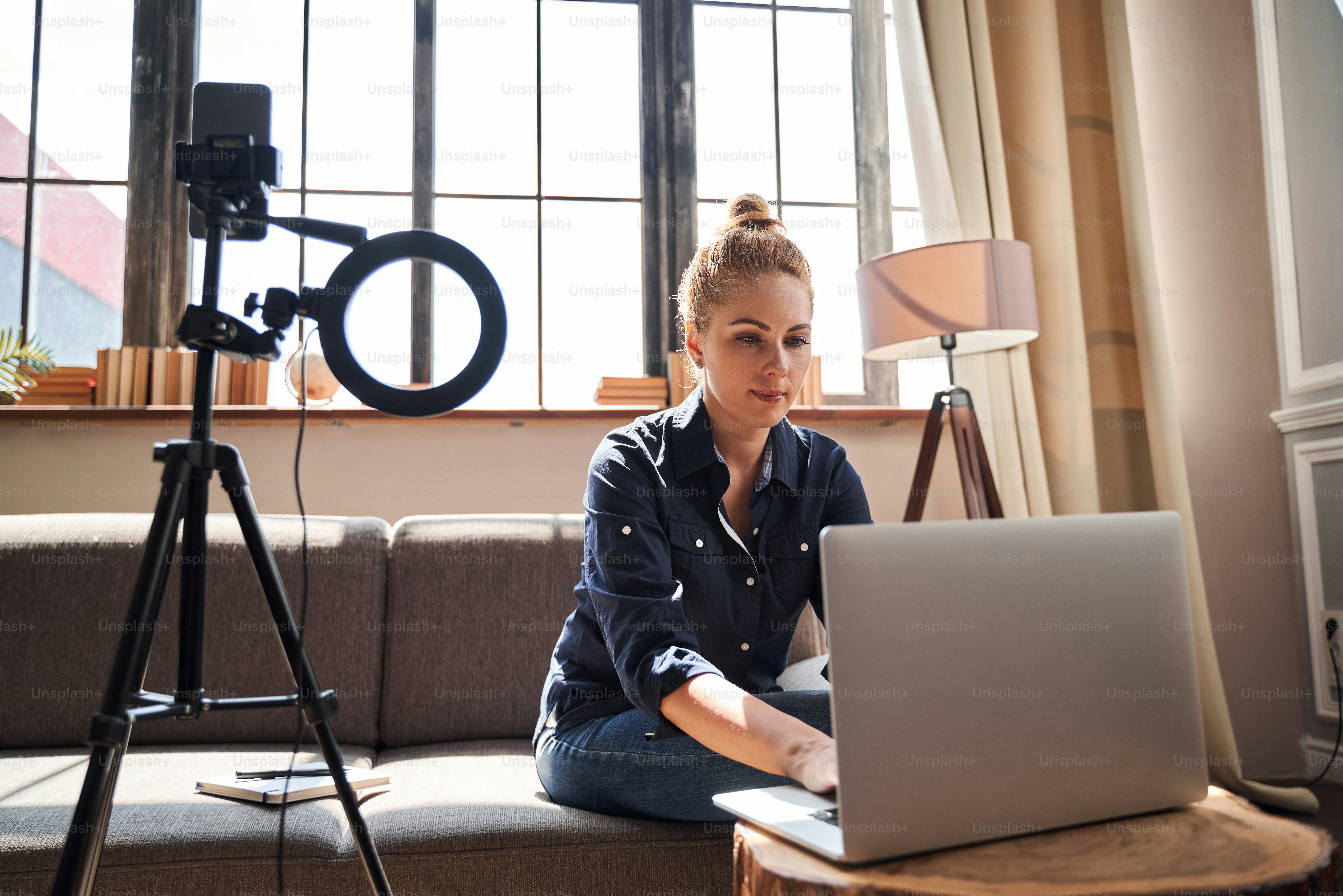 Beautiful Caucasian woman sitting on a sofa and looking at the screen of a modern laptop