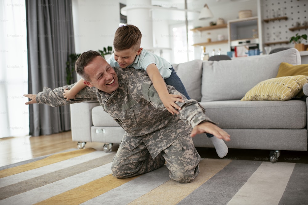 행복한 군인은 아들과 놀고 있습니다. 아이들과 함께 집에서 즐기는 군인.