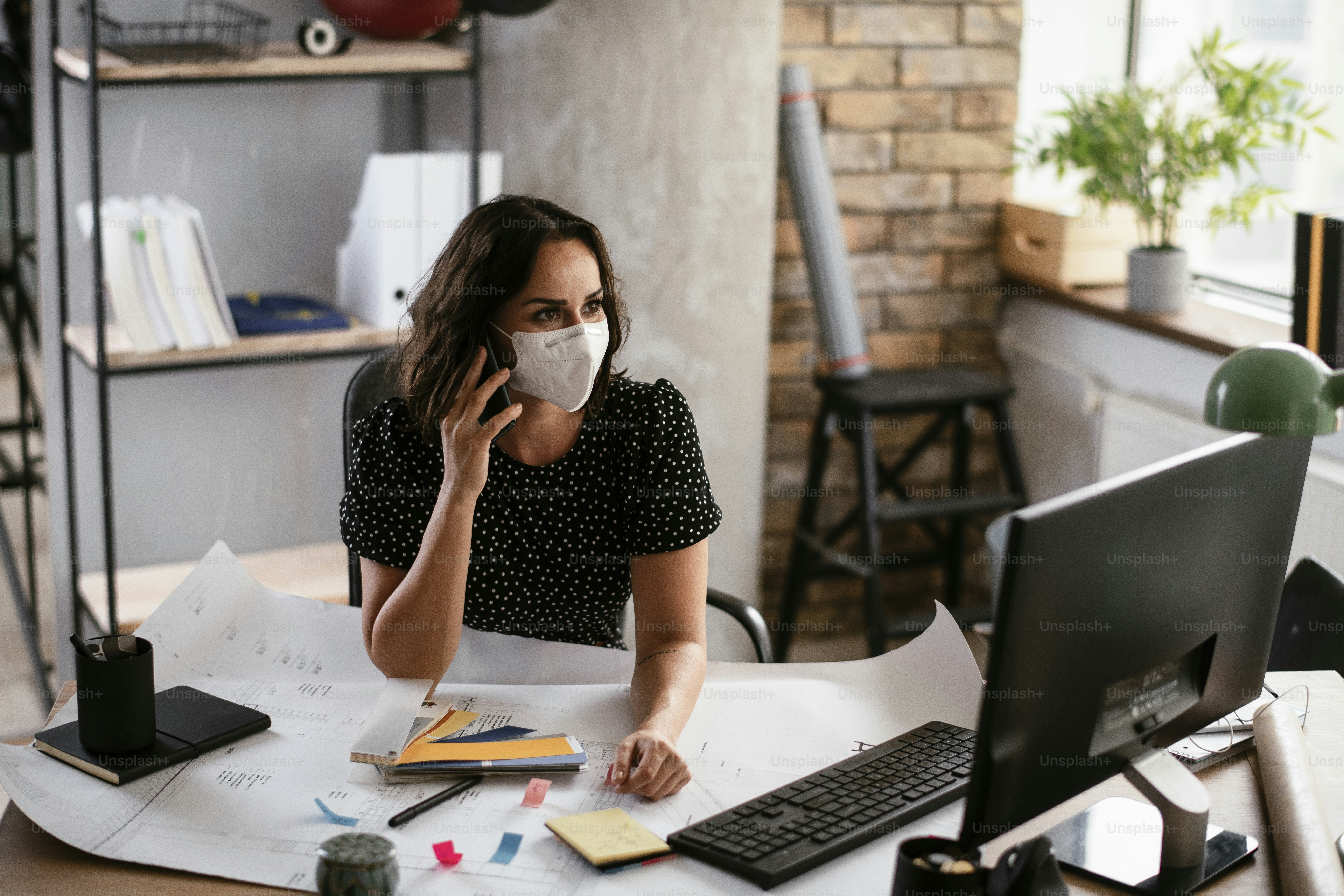 Femme d’affaires avec masque médical travaillant dans le bureau. Jeune femme parlant au téléphone