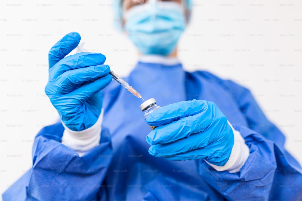 Médico, enfermera, científico, investigador mano en guantes azules sosteniendo la gripe, el sarampión, el coronavirus, la enfermedad de la vacuna covid-19 preparándose para ensayos clínicos en humanos vacuna vacuna, medicina y concepto de fármaco.
