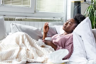 Sickness, seasonal virus problem concept. Woman being sick having flu lying on bed looking at temperature on thermometer. Sick woman lying in bed with high fever. Cold flu coronavirus, covid19