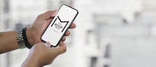 Close up view of male hands holding mock up smartphone on blurred office background