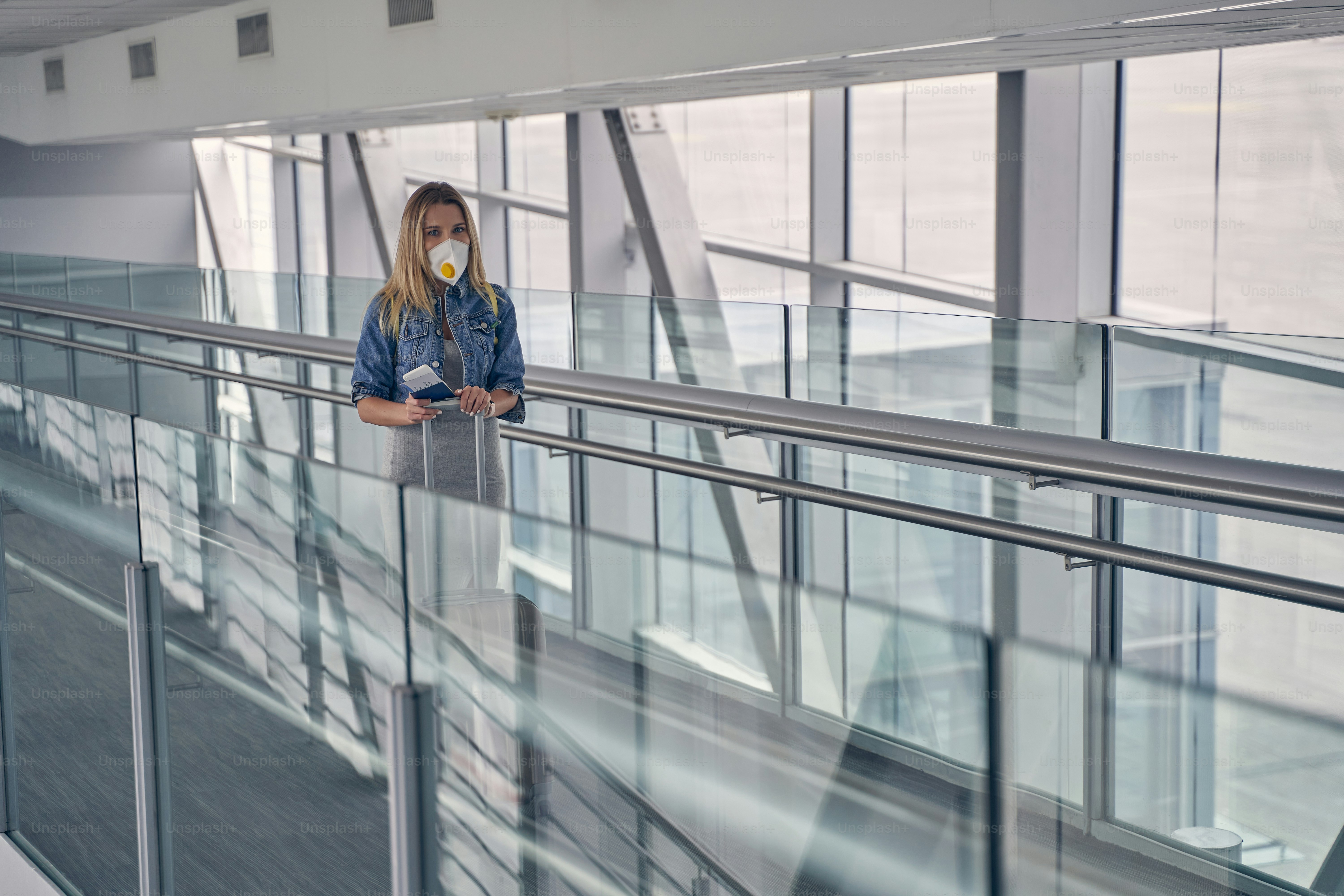 Delighted woman holding her boarding pass while preparing for the flight, standing in the corridor