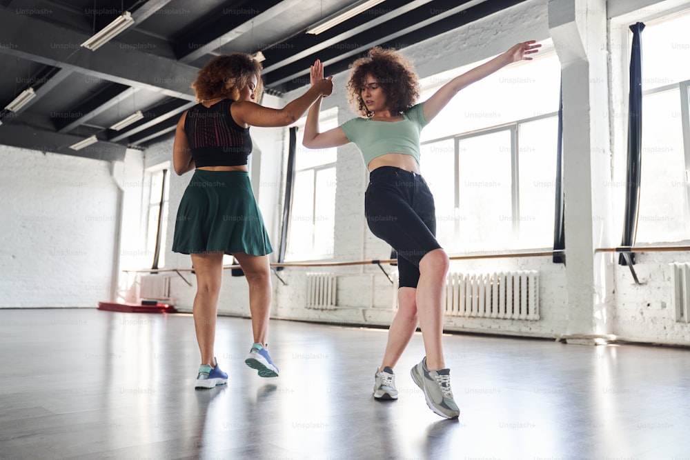 Full length photo of two female friends dancing modern dance