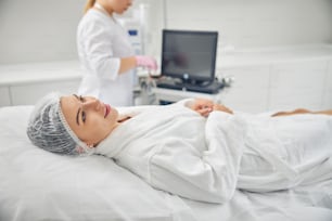 Jovem sonhadora deitada no sofá antes de um procedimento cosmético em um consultório dermatologista
