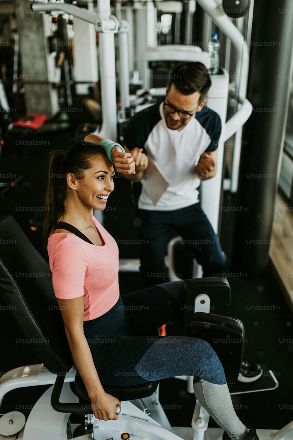 Young fit and attractive woman working out in modern gym together with her personal fitness instructor or coach.