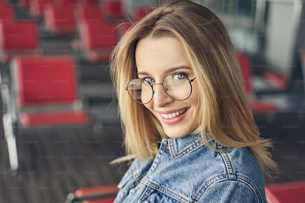 Beautiful blonde woman wearing stylish glasses while going to travel with pleasure alone