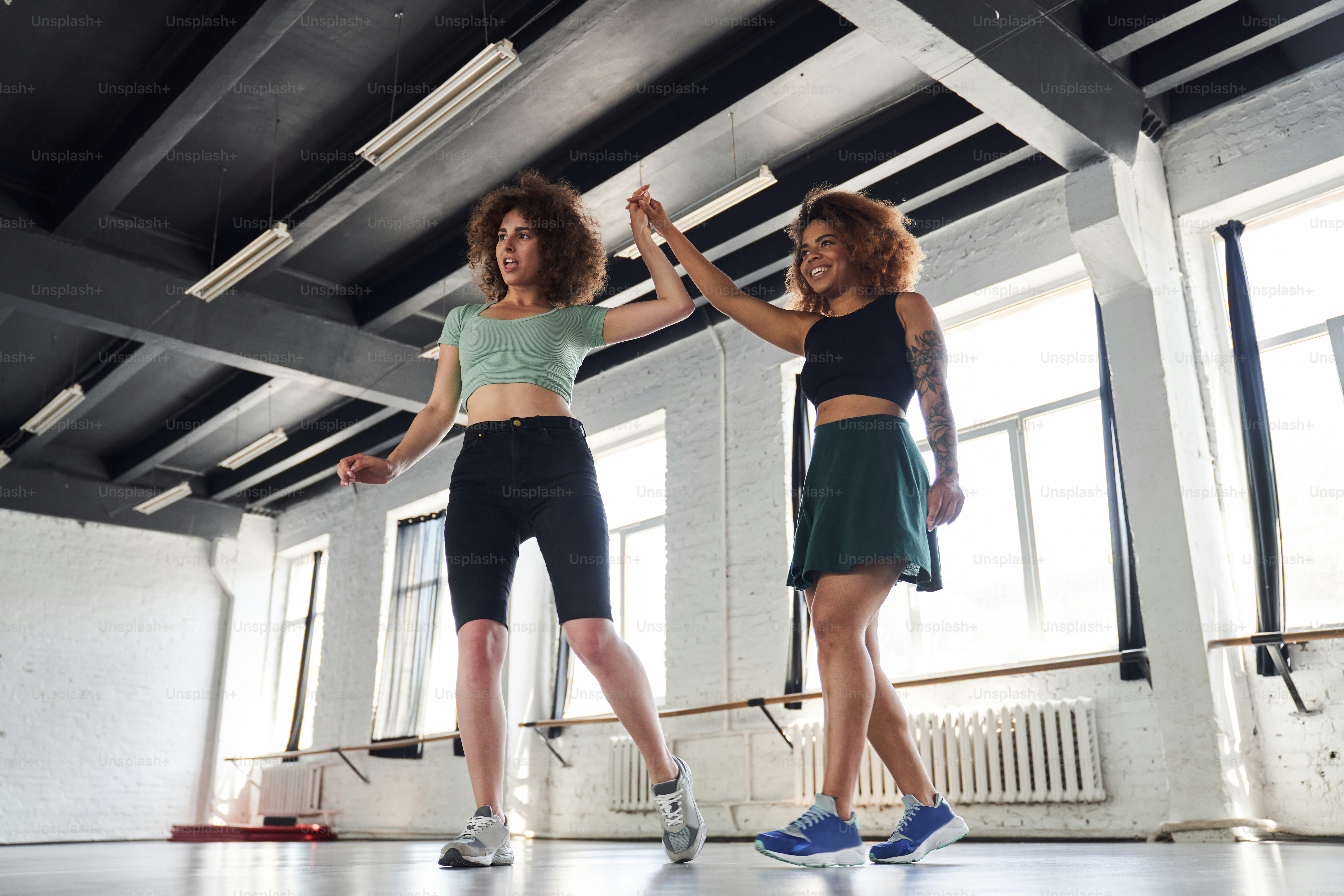 Full length photo of two happy pretty women improvising together in studio