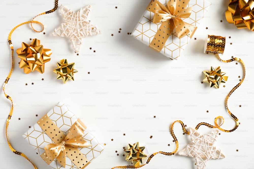 メリークリスマスと幸せな休日のグリーティングカード、フレーム、バナー。フラットレイクリスマスの黄金の装飾、豪華なギフトボックス、星、リボン、白い背景の紙吹雪。冬休みのクリスマスのテーマ。