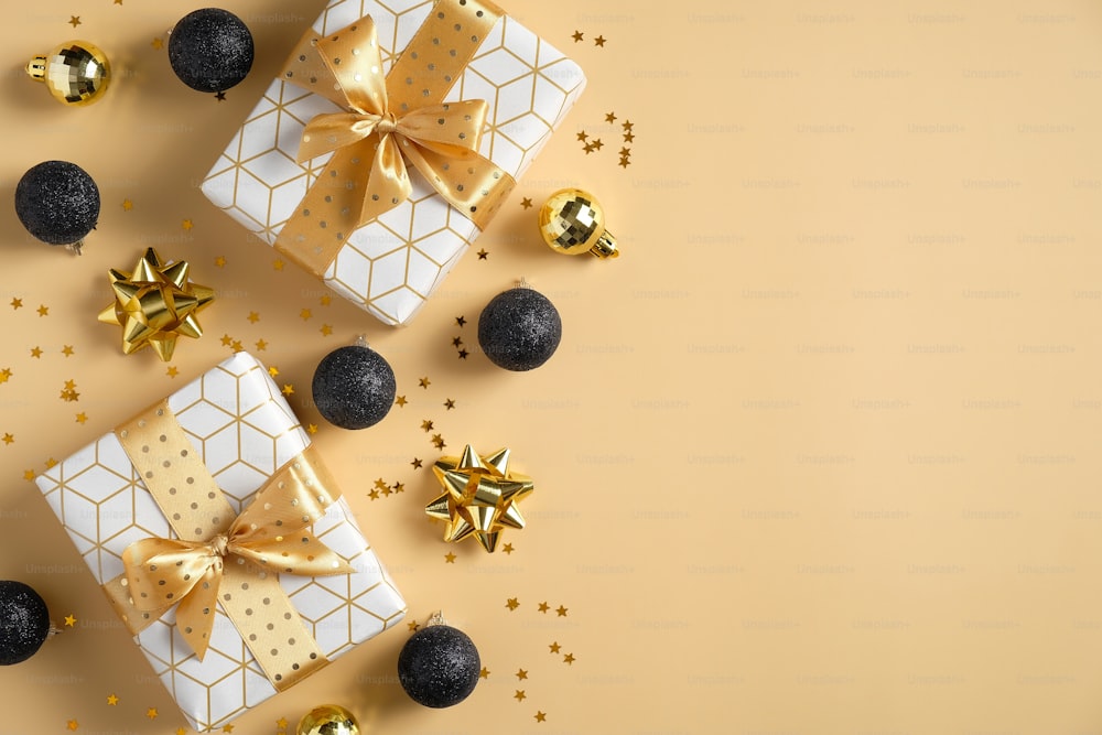 Modèle de carte de vœux de luxe de Noël avec des décorations dorées et noires. Plat lay, vue de dessus cadeaux de Noël, boules de Noël, guirlandes, confettis sur fond jaune pastel. Maquette de bannière de Noël.
