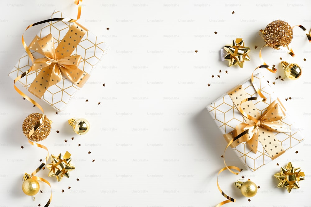 Weihnachtsrahmen aus goldenen Dekorationen und luxuriösen Geschenkboxen auf weißem Hintergrund. Flache Lage, Draufsicht. Weihnachtsgrußkarte, Neujahrsbanner-Mockup.