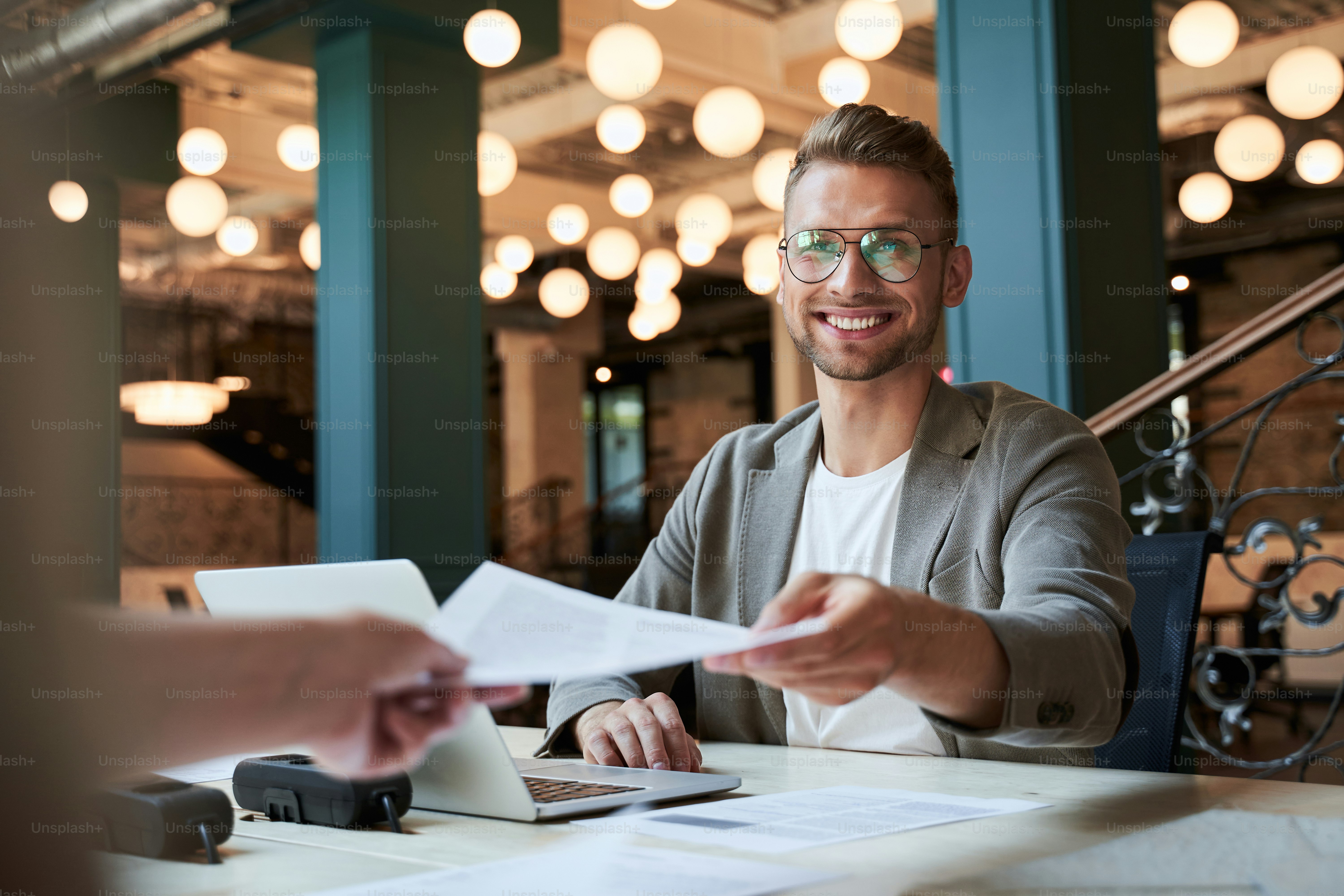 Giovane uomo d'affari allegro che sembra felice di aver passato alcune scartoffie mentre lavorava in ufficio