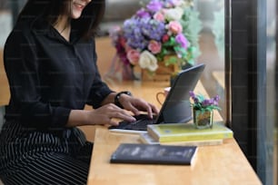 A woman is using a computer tablet while sitting at the wooden counter.