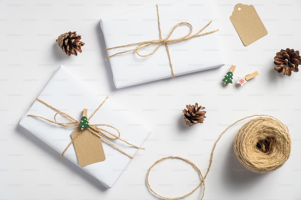 Christmas background with gift boxes, string rope, pine cones on white. Preparation for holidays. Eco friendly Christmas presents, zero waste concept.