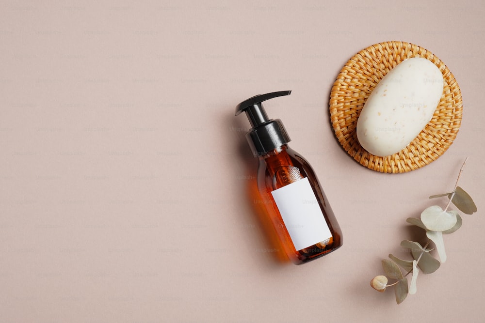 Amber glass shampoo dispenser bottle mockup, organic soap and eucalyptus leaf on brown background. SPA bathroom cosmetics set.