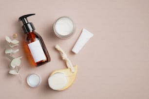 Set von SPA natürliche Biokosmetik. Pumpkosmetikflasche mit weißem Etikett, Handcreme, Gesichtsreinigungsbürste auf beigem Hintergrund.