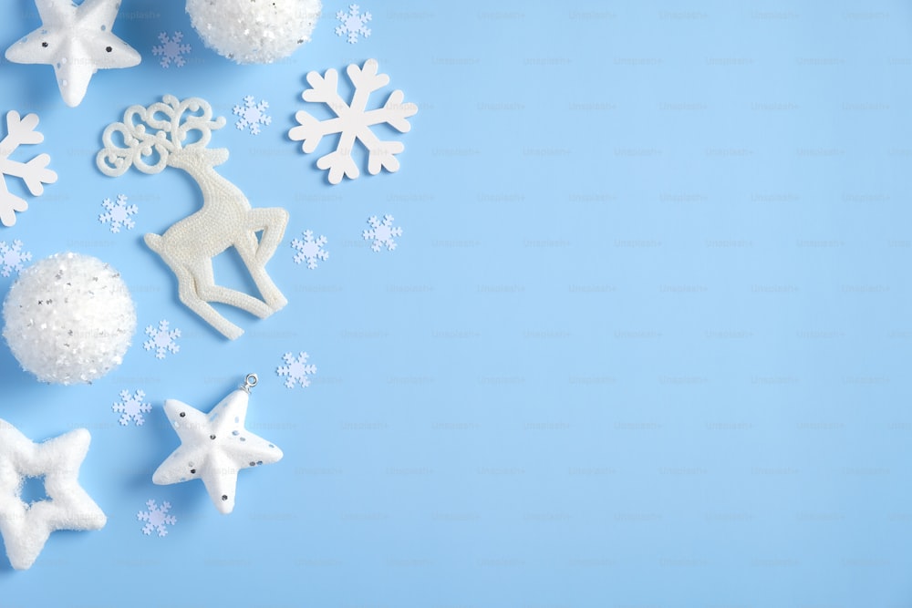 Flache Weihnachtskomposition. Draufsicht weiße Weihnachtsdekoration, Bälle, Sterne, Konfetti auf blauem Hintergrund. Weihnachtsgrußkarten-Mockup, Neujahrsbanner-Vorlage