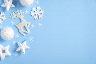 Composición navideña plana. Vista superior de decoraciones navideñas blancas, bolas, estrellas, confeti sobre fondo azul. Maqueta de tarjeta de felicitación de Navidad, plantilla de banner de Año Nuevo